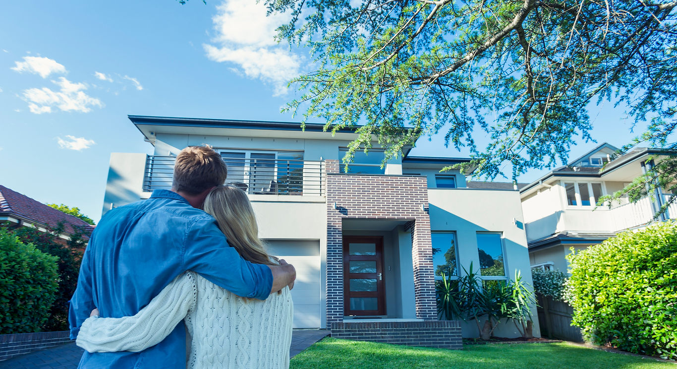 Couple standing in front of a bright modern home